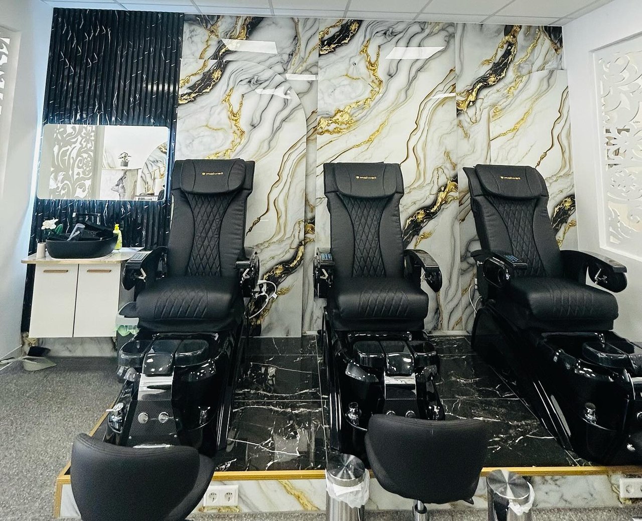 Three pedicure chairs in front of a marble wall